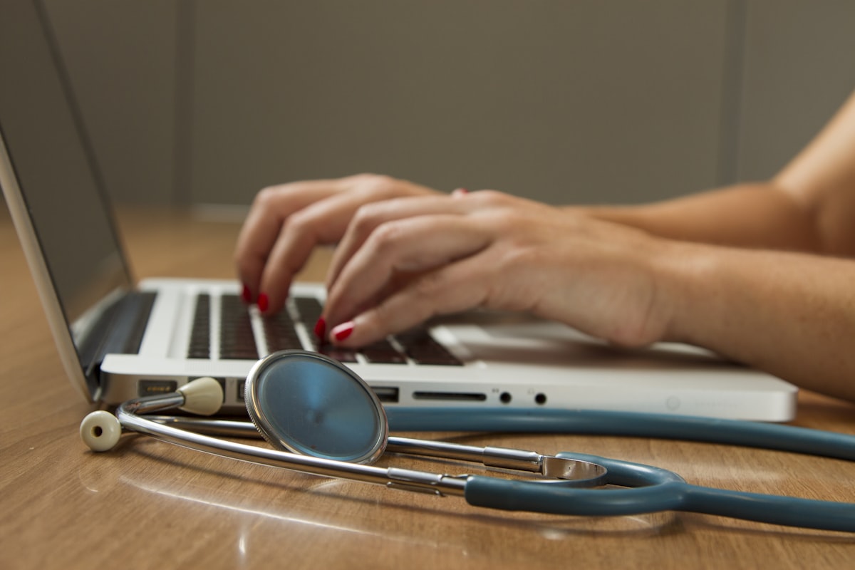 Healthcare professional reviewing insurance plan with stethoscope and laptop
